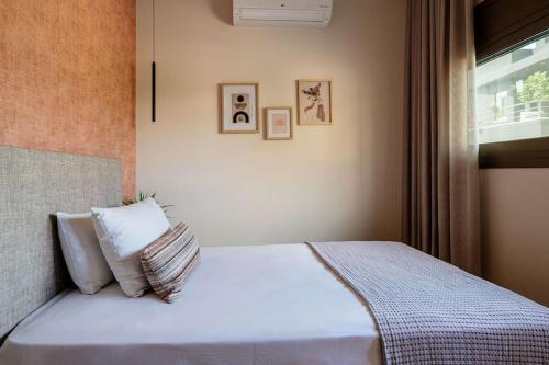海若克利欧Euphoria Luxury Apartment的一间卧室配有一张带白色床单的床和一扇窗户。