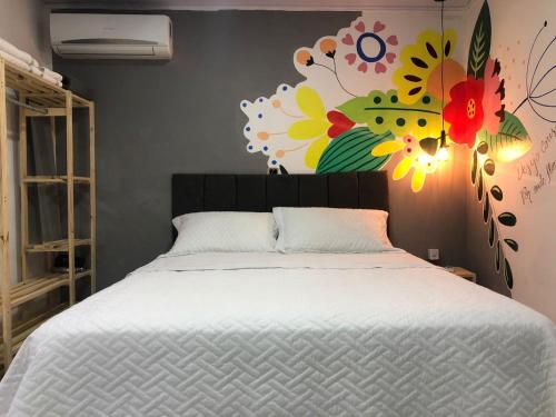 库亚巴Top Coliving I的卧室配有一张挂有花卉画的床铺。