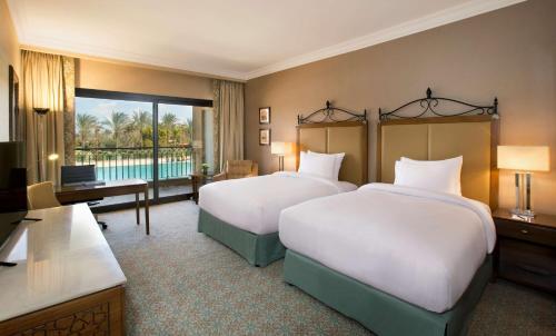 亚历山大Hilton Alexandria King's Ranch Hotel的酒店客房设有两张床和电视。