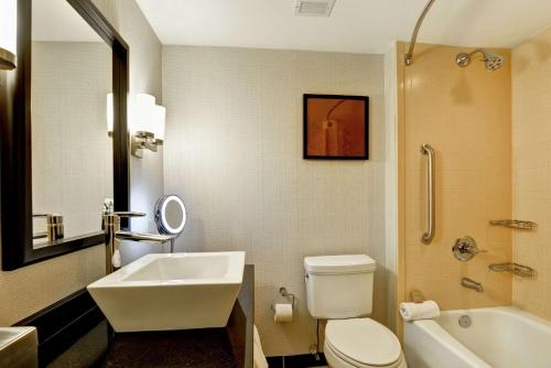 巴吞鲁日巴吞鲁日希尔顿逸林酒店的浴室配有盥洗盆、卫生间和浴缸。