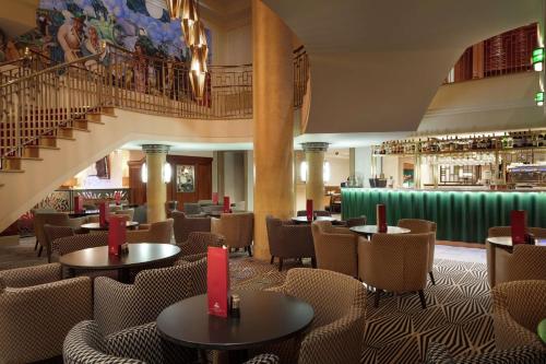 伦敦希尔顿伦敦帕丁顿酒店的一间带桌椅的餐厅,以及楼梯