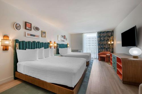 圣胡安Condado Palm Inn San Juan, Tapestry Collection by Hilton的酒店客房设有两张床和一台平面电视。