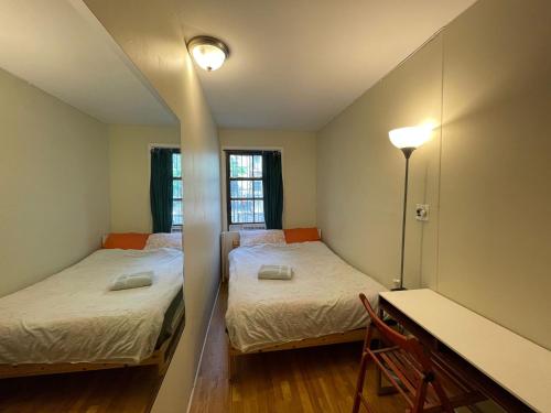 布鲁克林Central and Affordable Williamsburg Private bedroom Close to Subway的小型客房配有两张床铺、书桌和台灯。