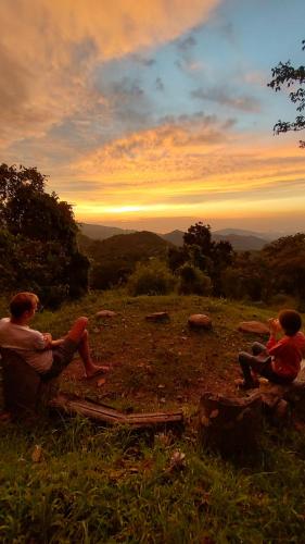 米卡Finca Hostal Bolivar - Casa Mango的坐在山坡上看日落的两个人