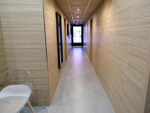 马德里Alianza Suites的走廊设有木墙和白色椅子