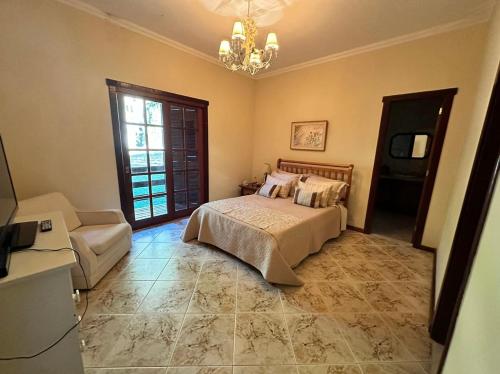 彼得罗波利斯Casa aconchego Secretário的一间卧室配有一张床、一张沙发和一个吊灯。