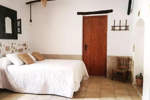 丘利利亚Casa Rural La Corretger的卧室配有白色的床和木门