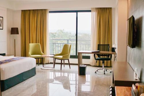 安吉利斯Hevea Hotel & Resort的酒店客房带一张床、一张桌子和椅子