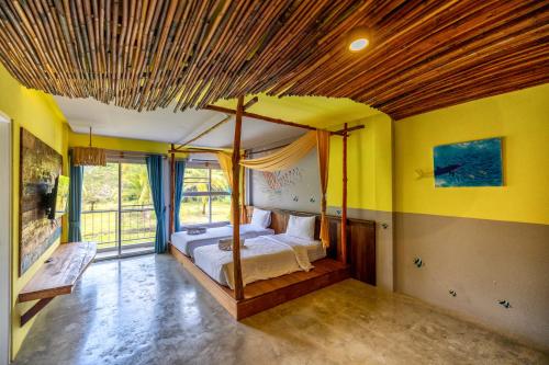 帕克蒙Dugong Village-Green Hotel的一间卧室设有四柱床和黄色的墙壁