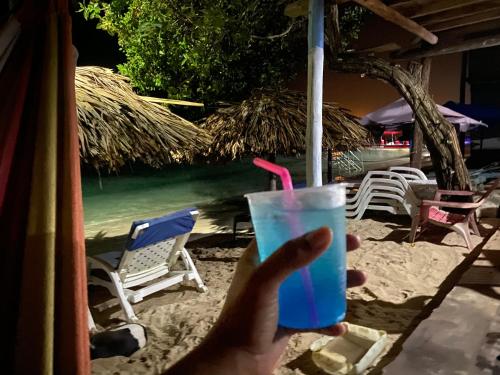 布兰卡滩Posada Shekinah Barú的手持蓝色饮料和粉红色的稻草