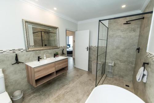 伊丽莎白港Tivoli Luxury Beach Apartment的浴室配有盥洗盆和带镜子的淋浴