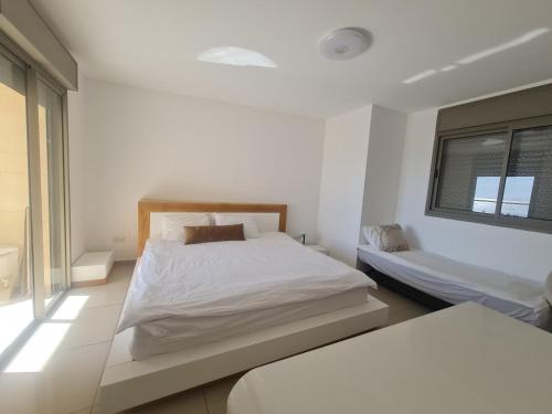 埃拉特Top-Luxury Exclusive Аpt with Jacuzzi in front of the sea的白色的卧室设有床和窗户