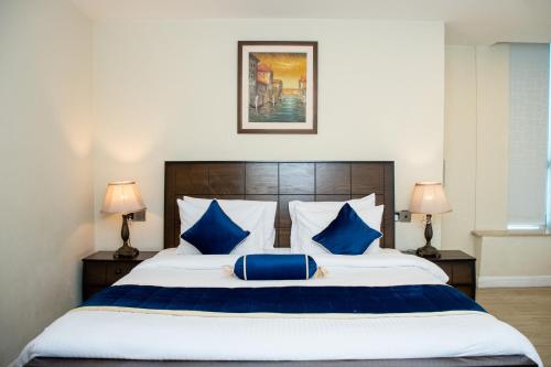 伊斯兰堡Centaurus Hotel Suites的一间卧室配有一张带蓝色枕头的大床