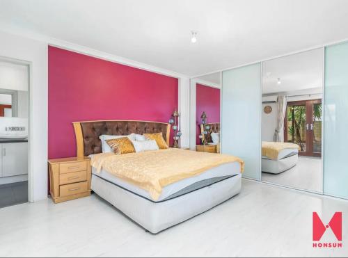 珀斯Leisurehome的一间卧室设有一张大床和粉红色的墙壁