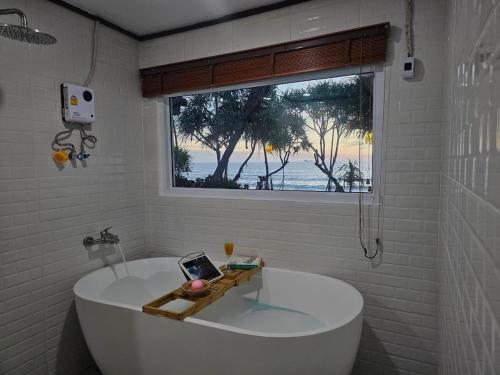 高兰Lanta Nice Beach Resort - SHA Extra Plus的带窗户的浴室内的白色浴缸