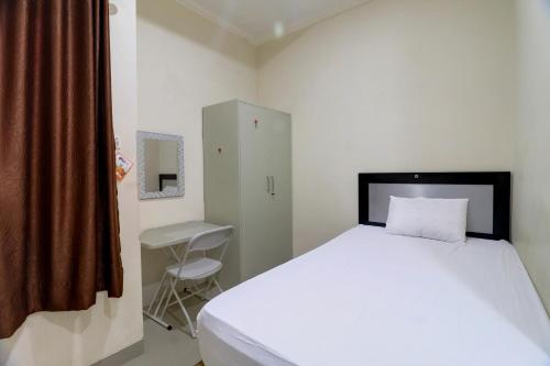 占碑市OYO Life 92707 D-akomiba Residence的卧室配有一张白色大床和一把椅子