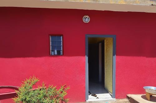 MamoudzouMaison 2 chambres avec jardin.的红色的建筑,有红色的墙壁和门
