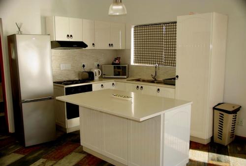 吕德里茨The Cormorant House的厨房配有白色橱柜和白色冰箱。