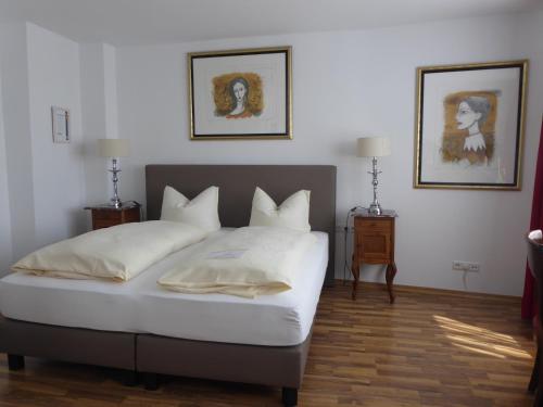 巴特洪内夫Hotel Weinhaus Hoff的卧室配有一张床,墙上挂有两张照片