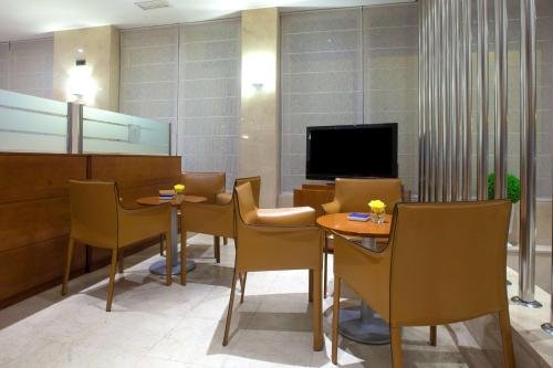 马贝拉NH San Pedro de Alcántara的一间设有桌椅和电视的等候室