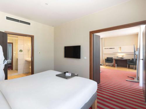 华沙华沙美居大酒店的酒店客房设有白色的床和客厅。
