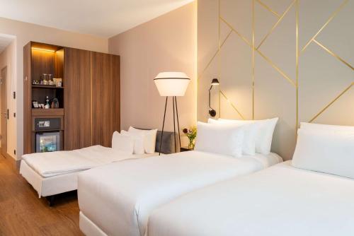 慕尼黑NH Collection München Bavaria的配有白色枕头的酒店客房内的两张床