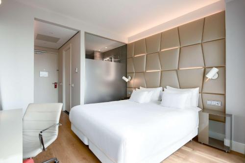 埃因霍温NH埃因霍温中心酒店的卧室配有一张白色大床和一把椅子