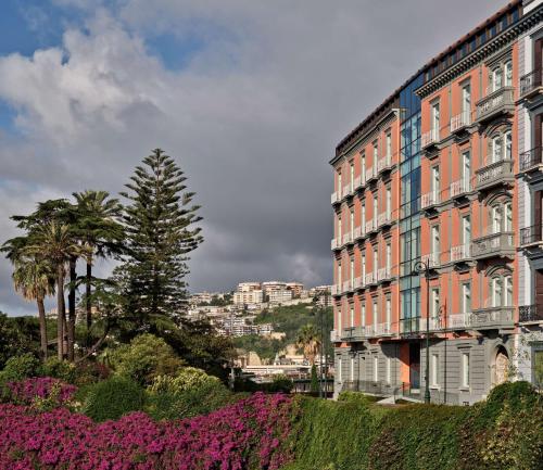 那不勒斯The Britannique Hotel Naples, Curio Collection By Hilton的一座大建筑前面有粉红色的花朵