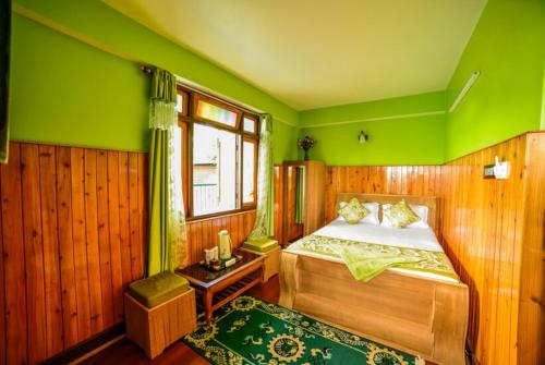 GhumGRG Tharbaling Homestay Darjeeling的一间卧室设有一张床和绿色的墙壁