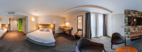 MerouxCampanile Belfort Montbéliard - Gare La Jonxion.的酒店客房,配有一张床和两把椅子