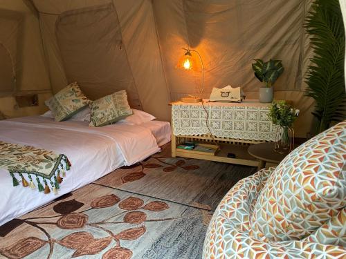 深圳NatureLand望桐露营地的帐篷间 - 带2张床和1张带台灯的桌子