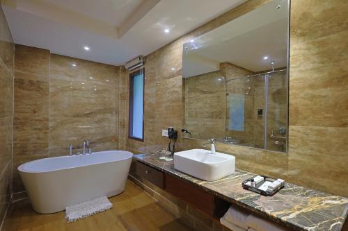 德拉敦Punarnava Wellness Resort & Spa的带浴缸、水槽和镜子的浴室
