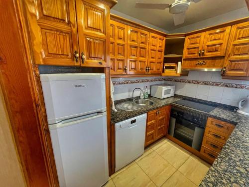 圣地亚哥港Puertito Varadero的厨房配有木制橱柜和白色冰箱。