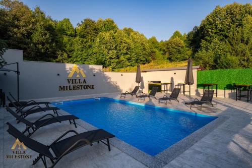 Villa Milestone Majevica的大楼前的带椅子和遮阳伞的游泳池