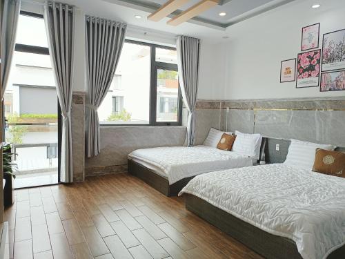 芹苴Thiên Lam Homestay的酒店客房设有两张床和窗户。