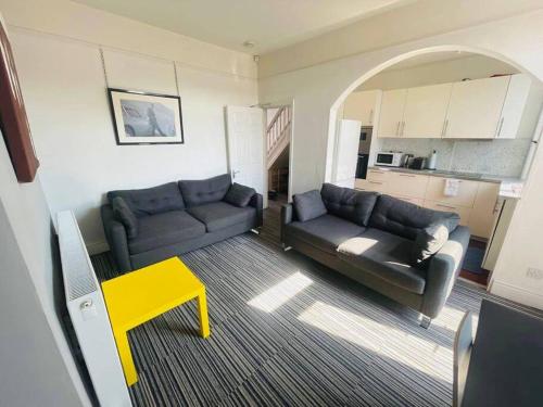 利物浦Stunning 4-BR Home near City Centre的客厅配有两张沙发和一张黄色的桌子