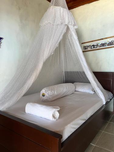 TapokrengMangkombong Homestay的一张带蚊帐的床和两张毛巾