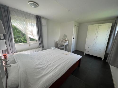 LithRuime chalet midden in de natuur in Lith的卧室设有一张白色大床和一扇窗户。