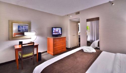 丹佛Embassy Suites by Hilton Denver Central Park的酒店客房配有一张床、一张书桌和一台电视。