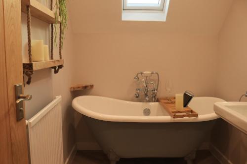 斯托昂泽沃尔德Beautiful Cottage in the Heart of Stow on the Wold的带浴缸和盥洗盆的浴室