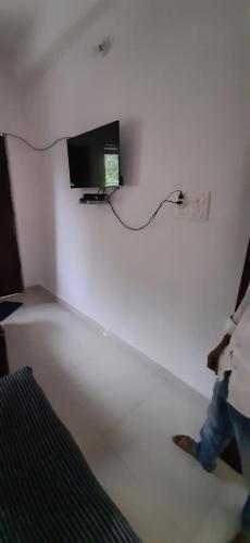 菩提伽耶Kalawati Niwas的一个人在墙上配有电视的房间散步