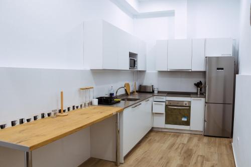 塞维利亚Triana Riverside Guesthouse的厨房配有白色橱柜和木制台面