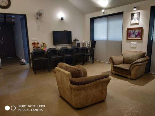 纳西克Forest Feels的客厅配有两把椅子和电视
