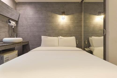 首尔HERTZ Hotel的卧室配有白色的床和水槽
