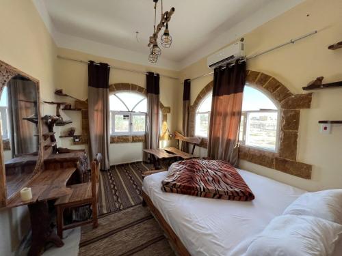 锡瓦People to People Hostel Siwa的卧室配有一张床、一张书桌和窗户。