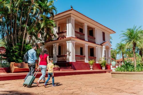 阿拉拉夸拉Hotel Fazenda Salto Grande的一家在房子前带行李散步