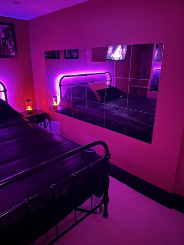 巴恩斯利The Indulging Basement的客房设有两张床和一面带紫色灯的镜子。