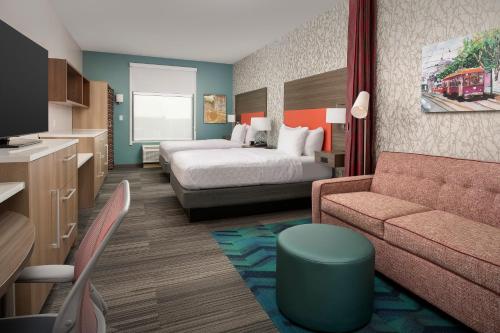 肯纳Home2 Suites By Hilton Kenner New Orleans Arpt的酒店客房,配有床和沙发
