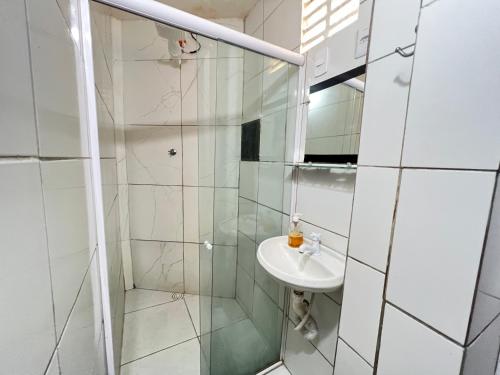 巴伊亚福尔莫萨Suítes Verano的一间带玻璃淋浴和水槽的浴室
