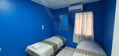阿皮亚Lynn's Getaway Guest House的蓝色的客房设有两张床和窗户。